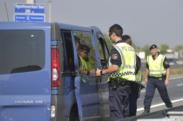 Policiais austríacos inspecionam veículo perto da fronteira com a Hungria em busca de imigrantes ilegais nesta segunda-feira (31) (Foto: Hans Punz/AP)