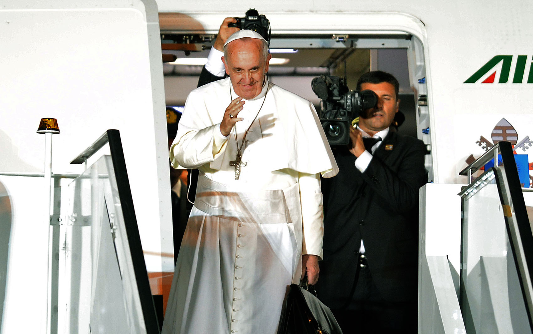 Pope Francis waves just before boarding the plane at the air base in Rio de Janeiro for his departure on July 28, 2013 as he concludes a week-long trip to Brazil. The head of the world's 1.2 billion Roman Catholics hammered home his plea for young believers attending World Youth Day (WYD) to "go and make disciples of all nations" as he concluded his trip to Brazil aimed at reigniting Roman Catholic passion. AFP PHOTO / EVARISTO SA